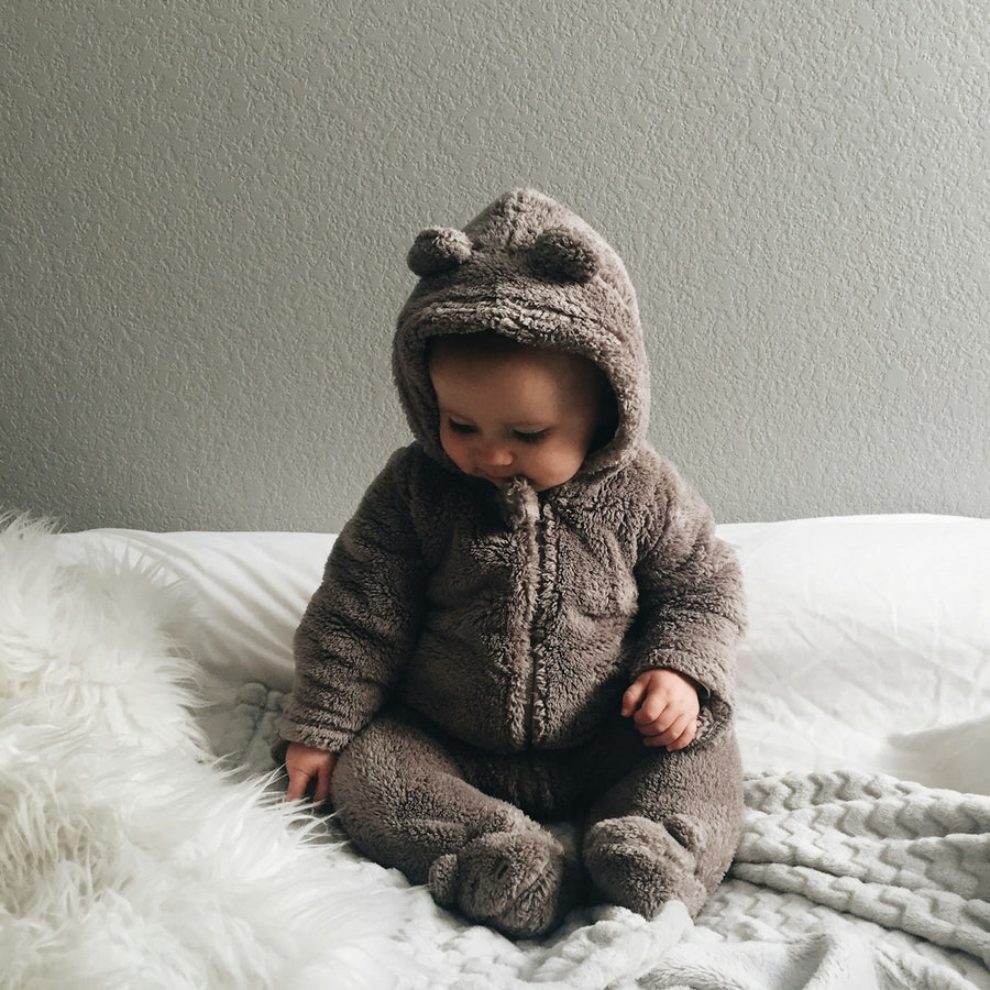 Baby in a cozy neutral onesie on a bed